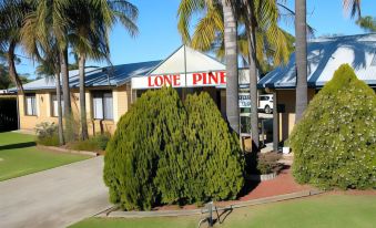 "a building with a sign that says "" lone pine "" and surrounded by trees and grass" at Lone Pine Motel