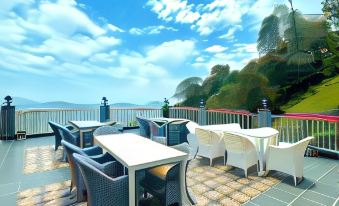 an outdoor dining area with a view of the ocean , featuring white tables and chairs at Wood Stock