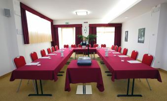 a conference room with a long table covered in red tablecloths , set up for a meeting at Best Western Cesena Hotel