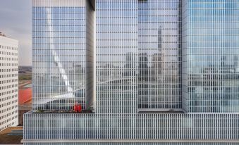 a large building with a glass facade and a view of the city in the background at Nhow Rotterdam