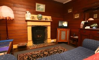 a cozy living room with a wooden wall , a fireplace , and a couch , creating a warm and inviting atmosphere at Westbury Gingerbread Cottages