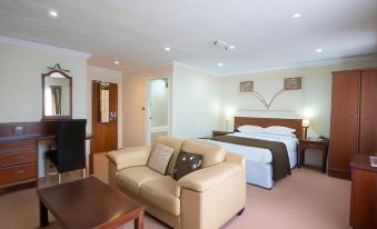a large , well - lit hotel room with a bed , couch , and dining table , all arranged in a comfortable and well - decorated atmosphere at Beaufort Park Hotel
