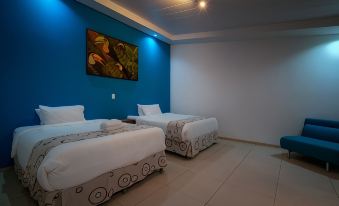 a room with two beds , a blue wall , and a painting of the same scene at Hotel Quelitales