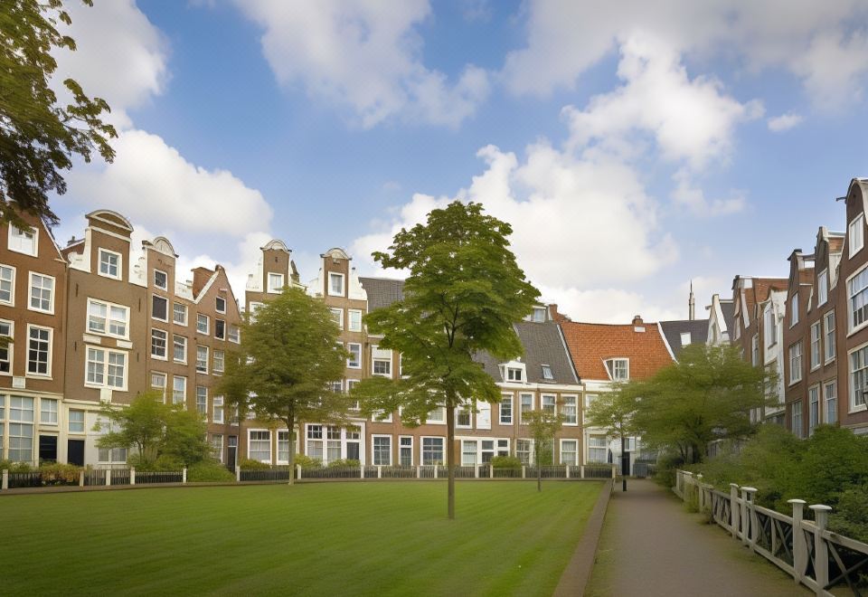 a courtyard with a grassy field , surrounded by a row of buildings and trees , under a cloudy blue sky at Nova Hotel