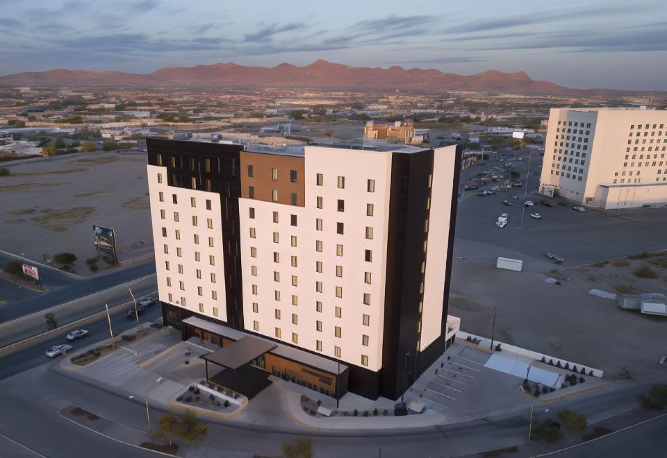 an aerial view of a hotel building surrounded by mountains and a parking lot in the background at Courtyard Ciudad Juarez