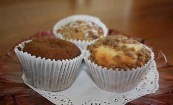 a white doily with three muffins on it , each containing a different flavor of frosting at Westbury Gingerbread Cottages