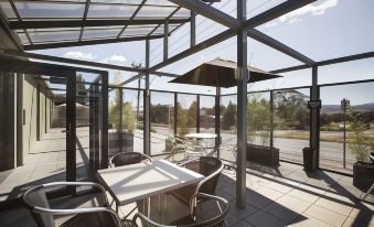 a glass - enclosed patio area with a table , chairs , and an umbrella , providing a pleasant outdoor dining experience at Nightcap at Riverside Hotel