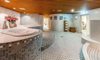 a large indoor pool area with a curved , tiled floor and walls , as well as a sauna at Fletcher Hotel-Restaurant de Klepperman