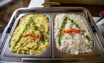 two trays of rice dishes , one with yellow rice and the other with white rice , placed on a dining table at AA Lodge Amboseli