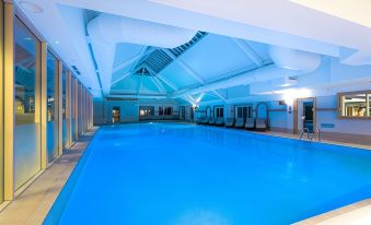 an indoor swimming pool with a blue and white color scheme , surrounded by a white building at The Park Royal Hotel & Spa