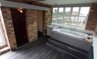a modern bathroom with a large bathtub and a walk - in shower , along with wooden floors and brick walls at Potbank