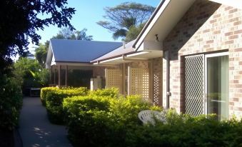 a brick house with a white railing and a potted plant in front of it at Redland Bay Motel