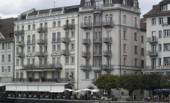 "a white building with a large balcony and the word "" hotel "" on it is situated next to a river" at Hotel des Balances