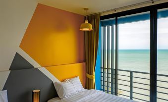 a bedroom with a large window offering a view of the ocean , and a bed with white sheets and pillows at Play Phala Beach Rayong