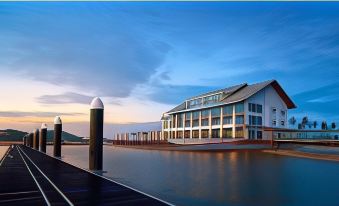 a large building is situated on a dock with a boat in front of it at Duyong Marina & Resort