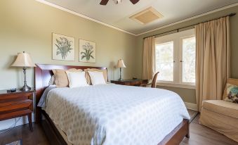 a large bed with a white comforter and brown headboard is in a room with a window at Arroyo Vista Inn