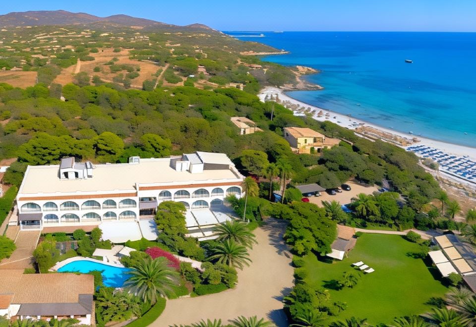 aerial view of a large white building surrounded by trees , located near the beach and a body of water at Hotel Simius Playa