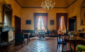 a large , dimly lit room with wooden floors and windows , containing several chairs and tables arranged in an open space at Castello di Semivicoli