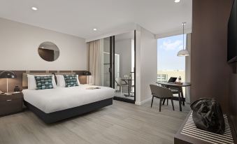 a modern hotel room with a large bed , wooden floors , and a balcony view of the city at Quest Innaloo
