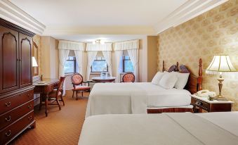 a hotel room with two beds , a dining table , and chairs , as well as a window overlooking the ocean at The Clarkson Inn