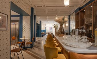 a modern , minimalist living room with blue walls and wooden floors , featuring a long dining table with chairs and various decorative items at Bristol Hotel