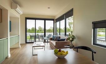 a living room with a couch , a dining table , and a view of a golf course at Berri Hotel