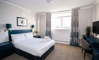 a clean and well - organized hotel room with a large bed , two nightstands , and a window at Birch Hotel