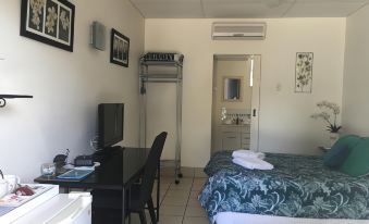 a hotel room with a bed , desk , and chair , as well as a bathroom with a shower at Black Marlin Motel