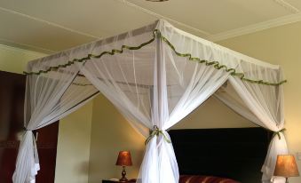 a large bed with a canopy and a lamp on each side of the bed at AA Lodge Amboseli