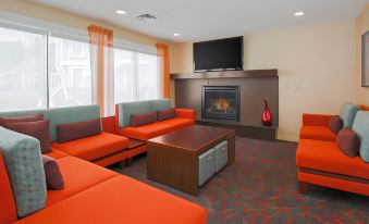 a modern living room with orange and blue furniture , a fireplace , and a television mounted on the wall at Sonesta ES Suites Cincinnati - Sharonville West
