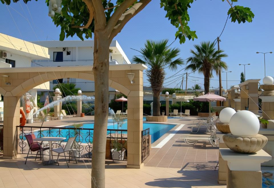 a large outdoor pool surrounded by lounge chairs and umbrellas , as well as a palm tree in the background at Hotel Antonios