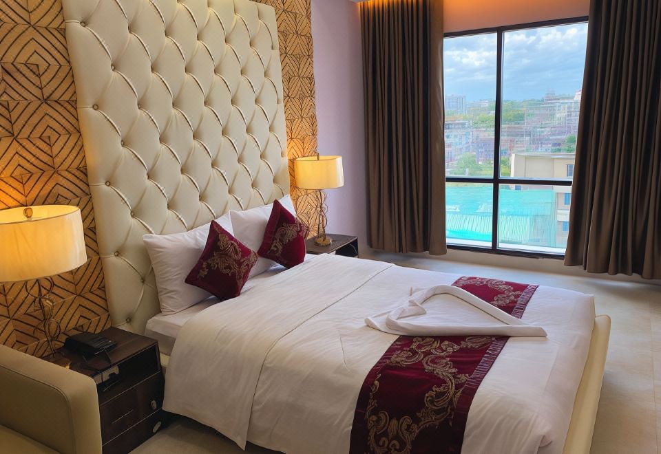 a large bed with a tufted headboard is situated in front of a window with a view of the ocean at Hotel Valentino