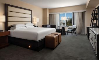 a modern hotel room with a large bed , brown leather seats , and a view of the city through a window at Hyatt Regency Sacramento