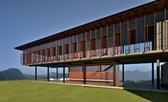 a modern house with a large porch and wooden exterior is surrounded by green grass at Santani Wellness Kandy