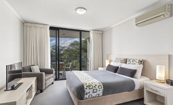 a bedroom with a large bed , a chair , and a sliding glass door leading to a balcony at Landmark Resort