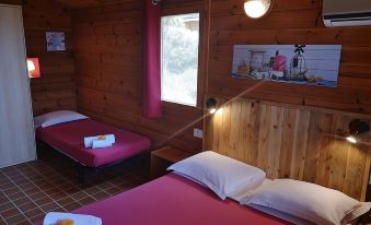 a cozy wooden cabin bedroom with two beds , white sheets , and a window offering views of trees at Mare E Monti