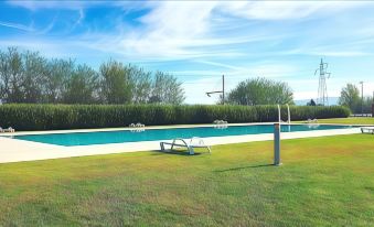 a grassy field with a swimming pool in the background , surrounded by trees and a fence at Inn Naples Airport