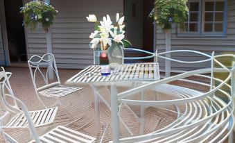 a white wrought iron table and chairs are set up on a patio with plants at Blue Pigeons