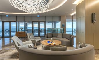 a modern lounge area with gray chairs , wooden tables , and large windows offering views of the ocean at Radisson Blu Hotel Trabzon
