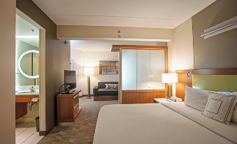 a large bed with white sheets is in a room with a television , lamp , and sliding glass door at SpringHill Suites Athens West