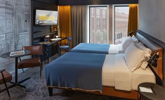 a modern hotel room with two beds , a desk , and a large window , giving it a cozy and stylish appearance at Hotel Brooklyn Manchester