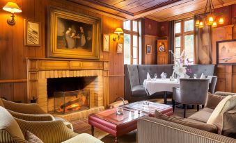 a cozy living room with a fireplace , a dining table , chairs , and a couch , all decorated in wood paneling at Hotel 115