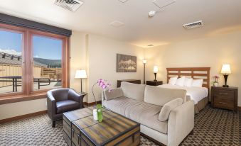 a modern hotel room with a large bed , white couch , and a flat - screen tv on the wall at The Village at Palisades Tahoe