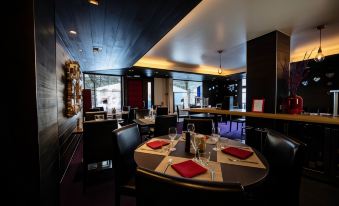 a modern restaurant with black chairs and tables , red napkins , and large windows offering views of the city at Avenue Lodge Hotel & Spa