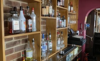 a bar with various bottles of liquor and liquor dispensers , creating an inviting atmosphere for patrons at The Ardingly Inn