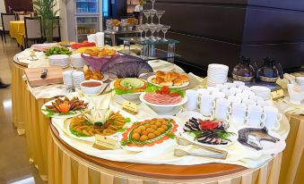 a table filled with a variety of food and drink items , including fruits , sandwiches , and beverages at Gold Hotel