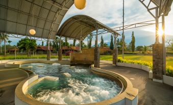 a large outdoor hot tub surrounded by grass and trees , creating a serene and relaxing atmosphere at Horison Tirta Sanita Spa Resort