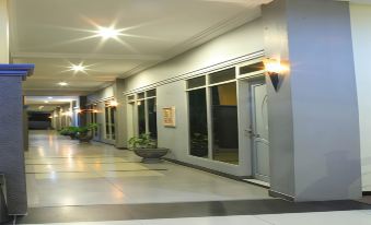 a long hallway with a potted plant on the left and several doors on both sides at Jazz Hotel Palu