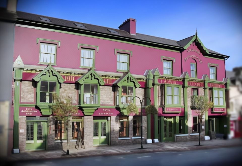 "a pink building with green trim and a red awning has a sign that says "" philz "" on the front" at Castle Hotel Macroom