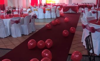 a large red and white room decorated for a wedding reception , with balloons scattered across the floor at My Hotel